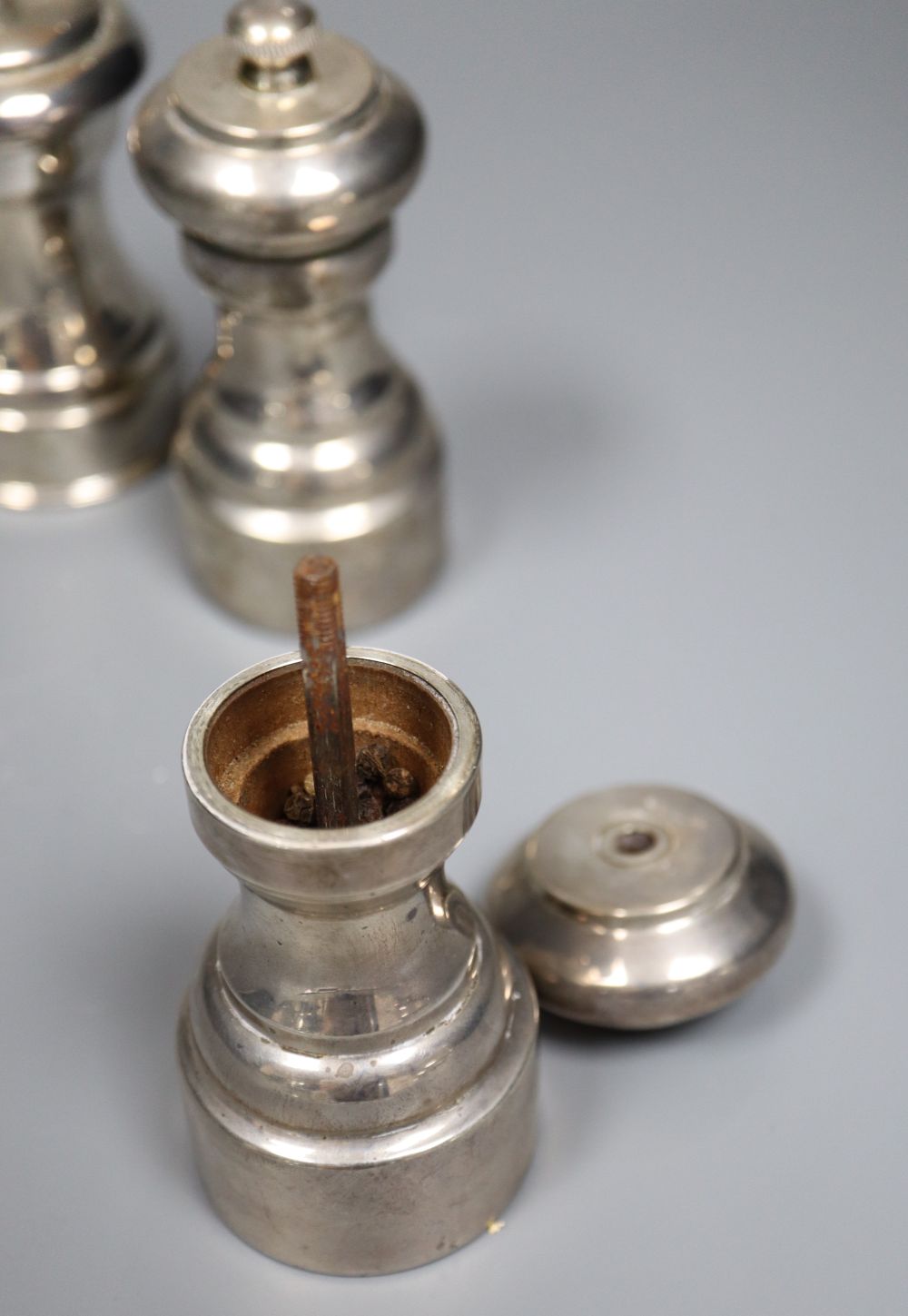 Three assorted modern silver mounted pepper mills, including a pair, London, 1980, tallest 10.5cm.